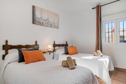 a bedroom with two beds with orange and blue pillows at Casa Pilar in Ronda