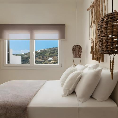 a white bed with white pillows and a window at Batsi view house in Andros