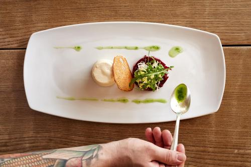 a plate of food with a person holding a spoon at Krone Hittisau - Hotel & Restaurant im Bregenzerwald in Hittisau
