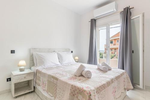 ein weißes Schlafzimmer mit einem Bett, auf dem zwei Handtücher liegen in der Unterkunft Rozario in Alepou