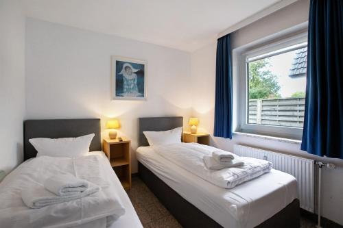 two beds in a room with a window at Sylt Ferienwohnung 1 Westerland in Westerland