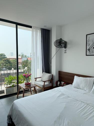 a bedroom with a bed and a chair and a window at Khánh Vy Homestay in Thôn Lại Thê
