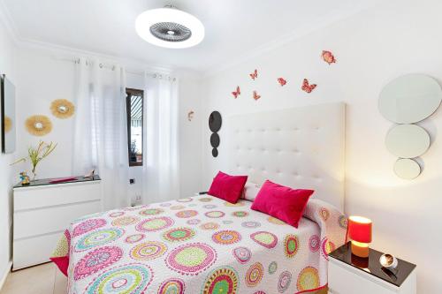 a white bedroom with a large bed with pink pillows at Alohe Puertorico View in Puerto Rico de Gran Canaria