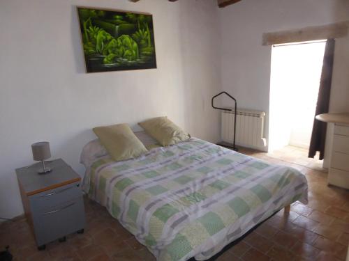 a bedroom with a bed and a nightstand and a picture on the wall at Maison de Village in Puimoisson