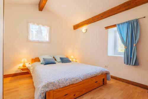 a bedroom with a bed and two windows at Gite de la Troulière in Banne