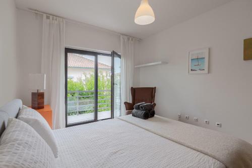 a bedroom with a bed and a chair and a window at Casa das Fontes - House of Wells in Parede