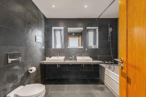 a bathroom with two sinks and a toilet at Casa das Fontes - House of Wells in Parede