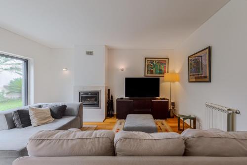 a living room with a couch and a tv at Casa das Fontes - House of Wells in Parede