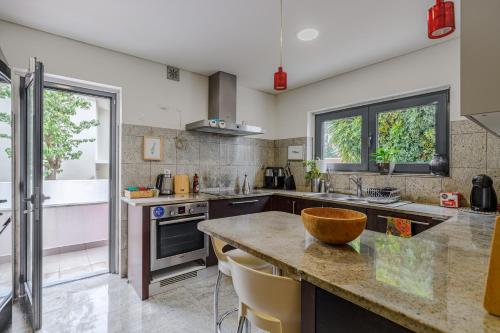 a kitchen with a counter and a sink and some windows at Casa das Fontes - House of Wells in Parede