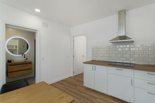 a kitchen with white cabinets and a table and a mirror at Los Mojones in Artenara