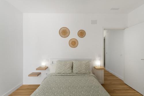 a white bedroom with a bed and two baskets on the wall at Los Mojones in Artenara