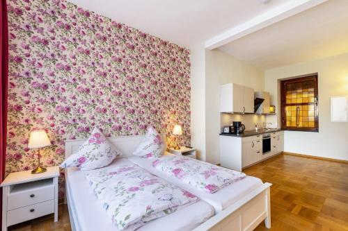 a bedroom with a white bed with pink floral wallpaper at Englisches Apartment in Kerken