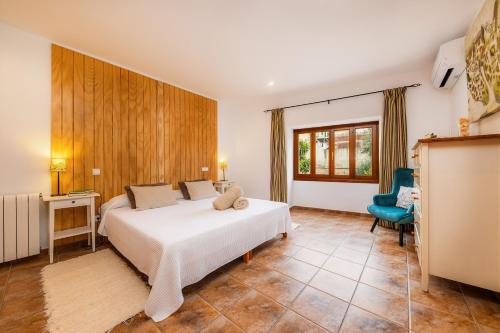 a bedroom with a white bed and a blue chair at Casa Hermosa in Capdepera