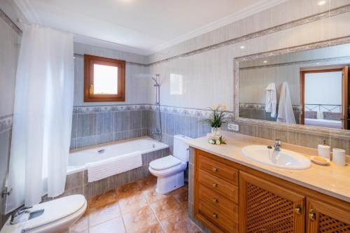 a bathroom with a tub and a toilet and a sink at Casa Hermosa in Capdepera