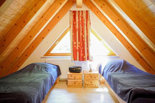 a attic room with two beds and a window at Wellehof in Oberkirch