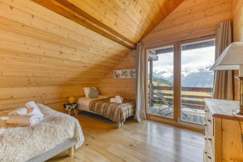 a log cabin with two beds and a large window at Chalet La Darse Nature et Sérénité in Villard-Reculas