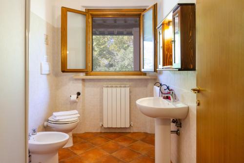 a bathroom with a toilet and a sink and a window at Bilo Hedera in Marina di Grosseto