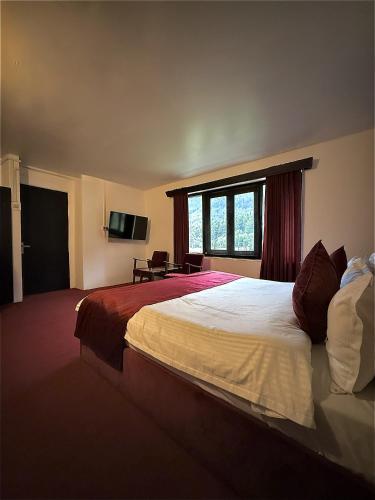 a hotel room with a large bed and a window at Riverdale by Stay Pattern in Pahalgām