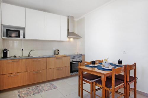 a kitchen with wooden cabinets and a table with chairs at A O - Augusta in Peniche