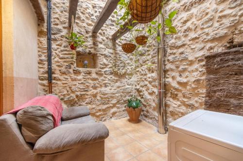 a living room with a chair and a stone wall at Casabras Rural in Claravalls