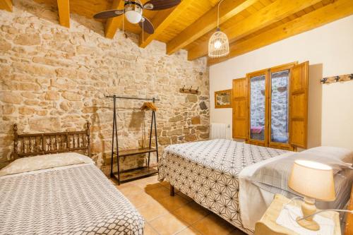 a bedroom with two beds and a stone wall at Casabras Rural in Claravalls