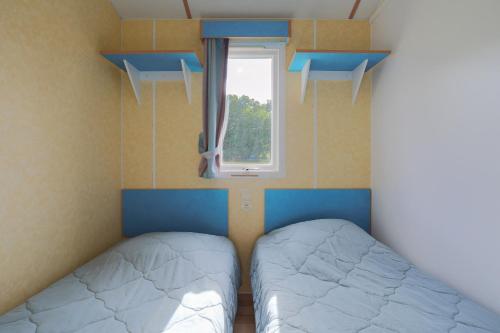 two beds in a small room with a window at Mobil home 2 Bikini in Plouha