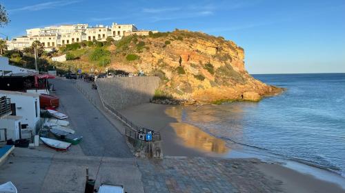 a beach with buildings on a hill next to the water at Burgau - A Casa dos Avós in Burgau