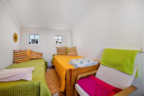 a small room with two beds and a chair at Burgau - A Casa dos Avós in Burgau