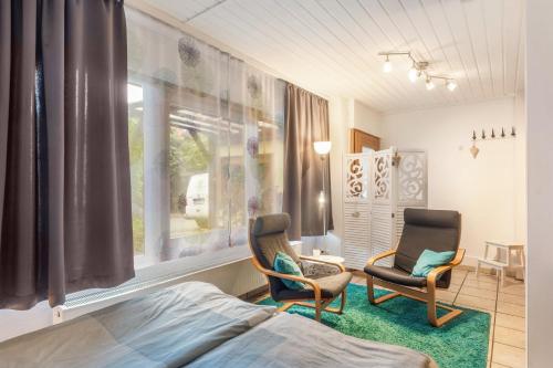 a bedroom with two chairs and a bed and a window at 1 Zimmer Ferienwohnung in Lohfelden