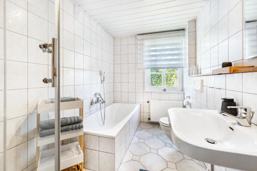 a white bathroom with a tub and a sink at Fewo Allezeit Sauerland in Drolshagen
