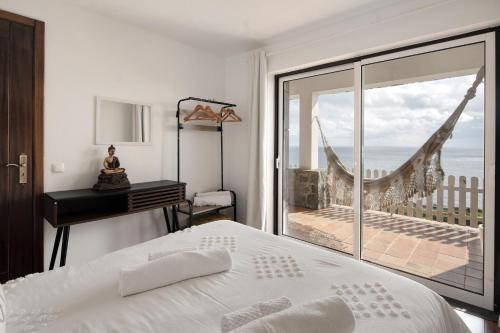 a bedroom with a bed and a view of the ocean at Breathe Nature - Beach House Azores in Feteira