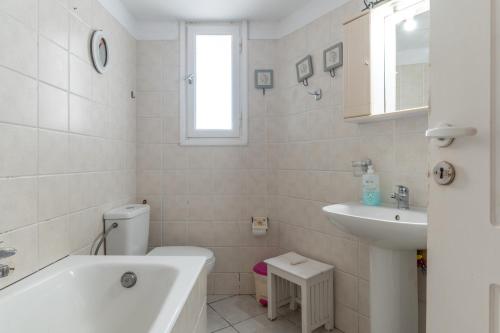 a white bathroom with a tub and a sink at Charmante ferienwohnung in Tinos