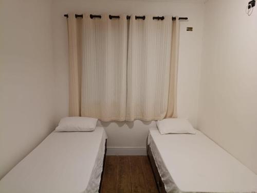 two beds in a small room with a window at Rancho das Estrelas in Gonçalves