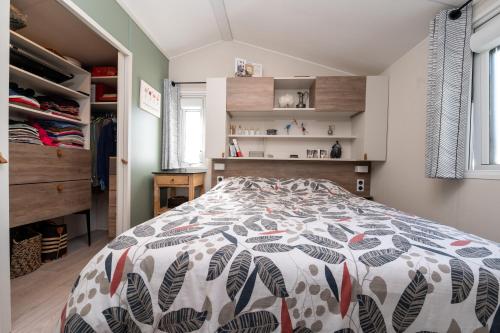 a bedroom with a bed with a colorful comforter at Mobilhome - Piscine - Premium in Erdeven