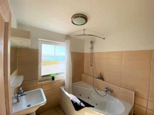 a bathroom with a tub and a sink at Strand Hus by Seeblick Ferien in Olpenitz