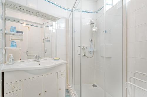 a white bathroom with a sink and a shower at Appartement Le Rial - Erquy in Erquy