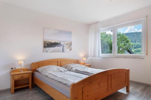 a bedroom with a wooden bed and two windows at Haus Reiser in Alpirsbach
