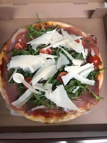 a pizza with cheese and greens in a box at Apartment Ballova in Balve