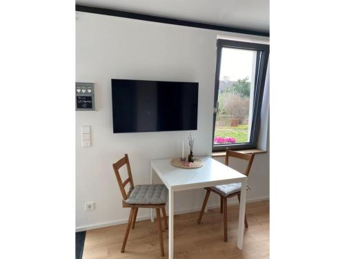 ein Esszimmer mit einem weißen Tisch und Stühlen und einem Fernseher in der Unterkunft Albnest in Mössingen