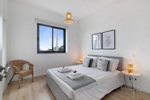 a white bedroom with a large bed and a chair at Formosa Home in Faro