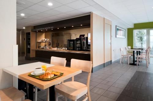 a kitchen and dining room with a table and chairs at B&B HOTEL Lyon Sud États-Unis in Vénissieux