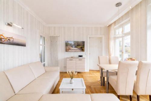 a living room with white furniture and a table at Villa Gruner Nr 13 in Zinnowitz