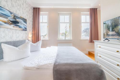 a white bedroom with a large bed and windows at Villa Gruner Nr 13 in Zinnowitz