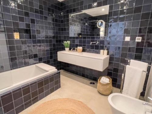 a bathroom with a tub and a sink and a bath tubermott at Jasmine House in Tavira