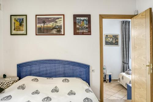 a bedroom with a blue bed and pictures on the wall at Villa Empuries A2 in Empuriabrava