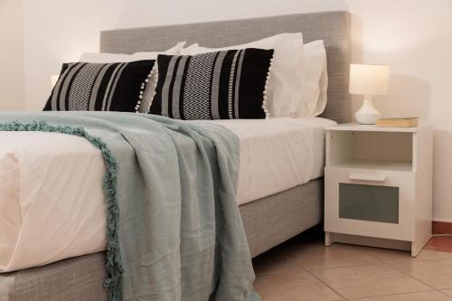 a bed with white and black pillows and a night stand at Villa Kairos Naxos in Glinádhon