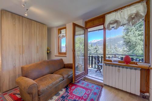 a living room with a leather couch and a balcony at Studio La Borracina Mountain View - Happy Rentals in Sauze dʼOulx