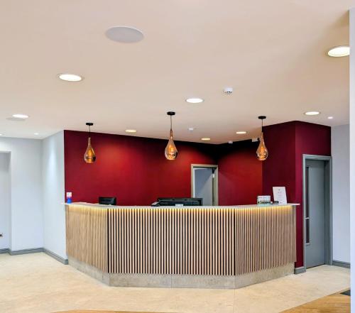 a hotel lobby with red walls and a reception desk at Passage House Hotel in Newton Abbot