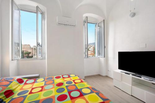 a white room with a bed and a flat screen tv at Domus Madonnina in Sanremo