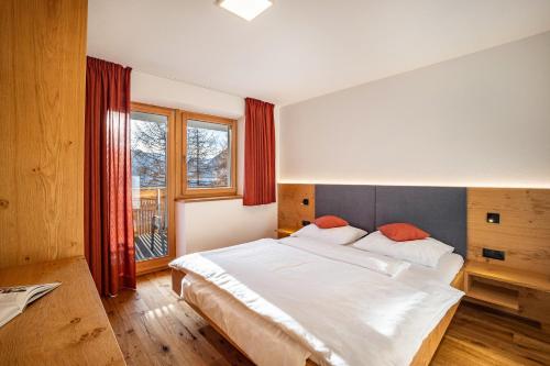 a bedroom with a large white bed and a window at App Hubertus - Moosstock in Sand in Taufers